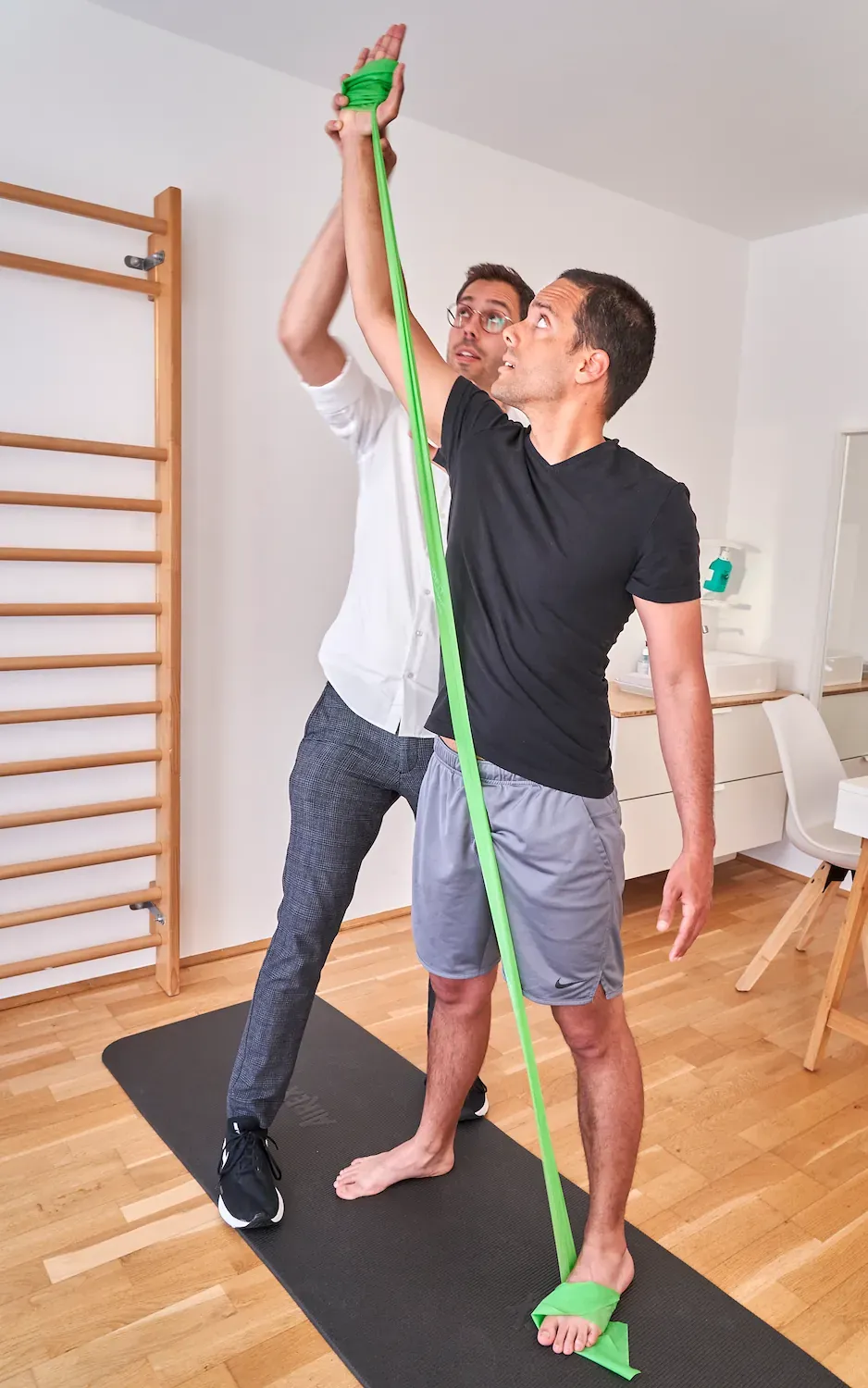 Leonard Handke macht mit einem Patienten eine Übung mit einem Theraband.